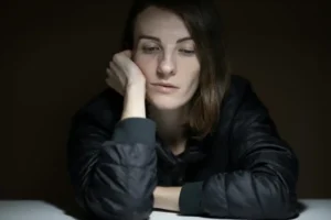 mujer con la cabeza apoyada en la mano y con una cara triste